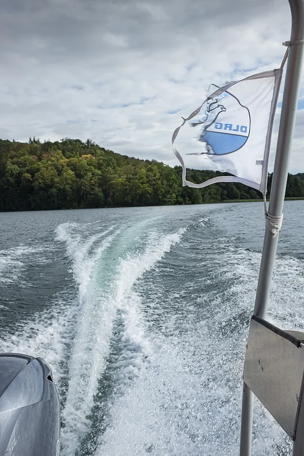 Fahrwasser des DLRG-Boots. Am Fahnenmast des Bootes flattert eine zerrissene DLRG-Flagge.