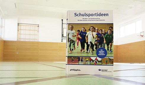 Das Buch Schulsportideen steht in einer Turnhalle. 