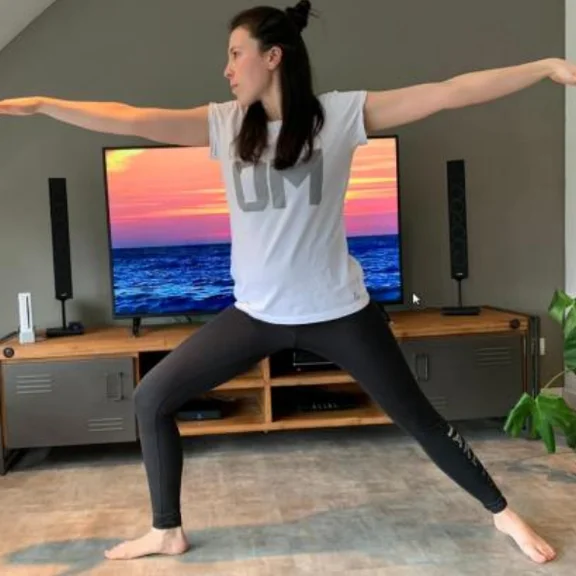 Frau im Wohnzimmer macht Yoga.