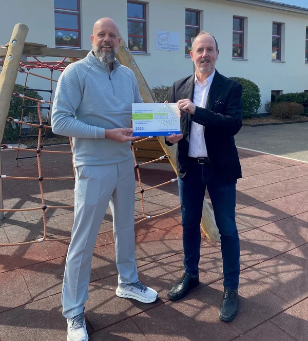 Zwei Männer. Der eine reicht dem anderen die Präventionspreis-Plakette.