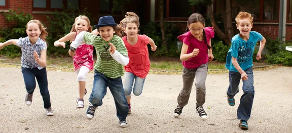 Sechs Kinder rennen auf einem Platz. 