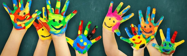 Bematlte Kinderhände vor einer Schultafel