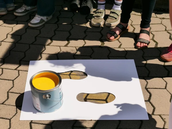 Eine Schablone und ein Topf mit gelber Farbe steht auf dem Bürgersteig.