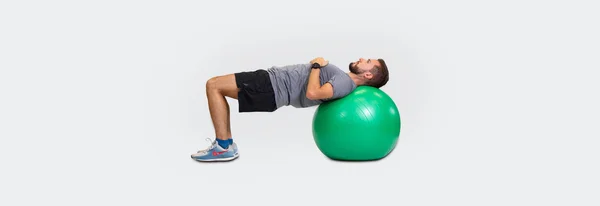 Ein Mann macht eine Übung für die Rückenmuskulatur mit dem Ball.