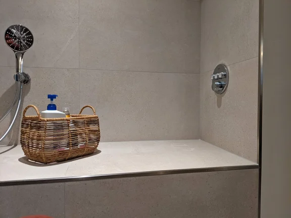 Selbst geplante Dusche mit seitlicher Armatur und Sitzbank.