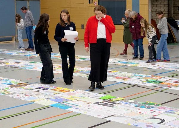 Mehrere Personen stehen zwischen den ausgestellten Bildern und betrachten sie.