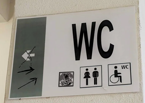 Irreführender Wegweiser zu einer Toilette.
