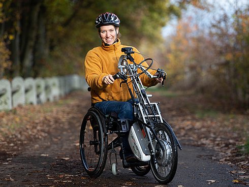 Die Autorin Sabrina Busch mit ihrem Handbike auf einem Fahrradweg in herbstlicher Umgebung