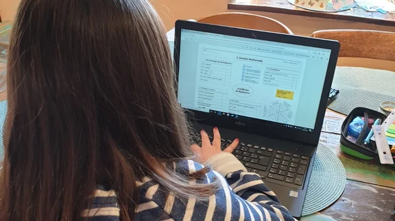 Schule zuhause: Mädchen sitzt zuhause am Laptop.