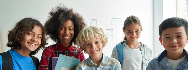 Fünf jugendliche Schulkinder stehen nebeneinander und blicken lachend in die Kamera.