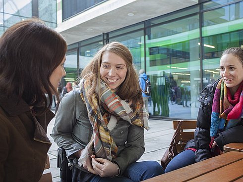 Die Autorin Sabrina Busch mit zwei Freundinnen am Tisch sitzend in einer Fußgängerzone