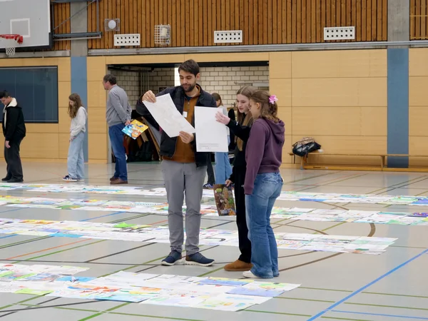 Drei Jury-Mitglieder mit mehreren Bildern in den Händen.