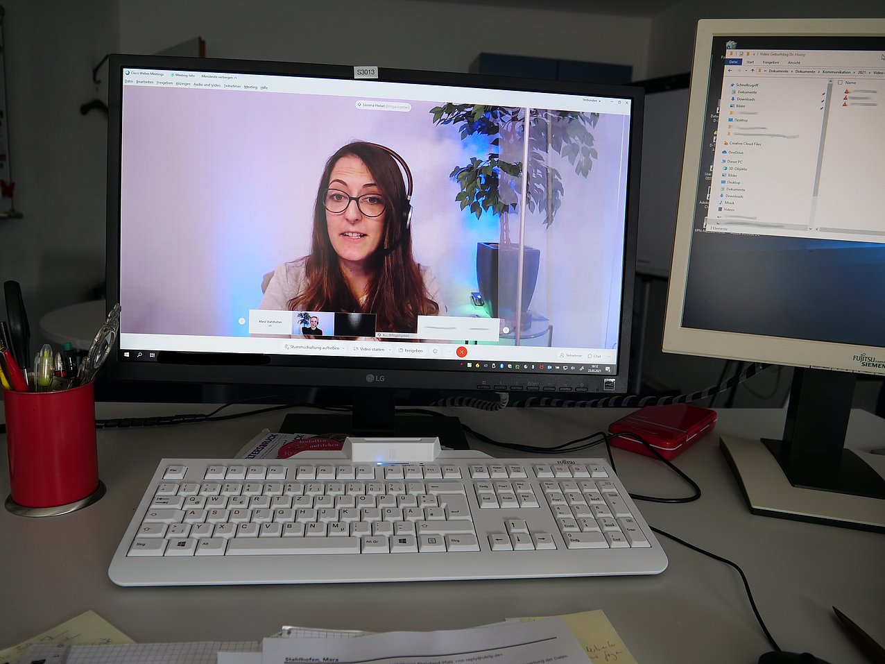 Eine Frau mit Kopfhörer spricht in einer Videokonferenz.