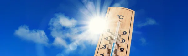 Ein Thermometer zeigt bei strahlendem Sonnenschein und blauem Himmel eine Temperatur an.