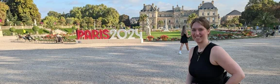 Eine Frau im Rollstuhl, im Hintergrund der Schriftzug "Paris 2024".