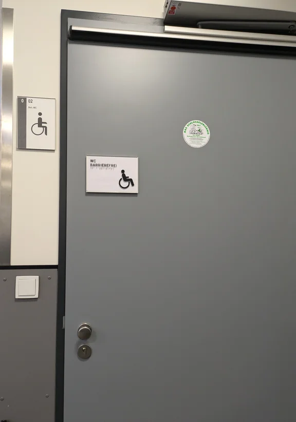 Die geschlossene Tür einer Behindertentoilette von außen.