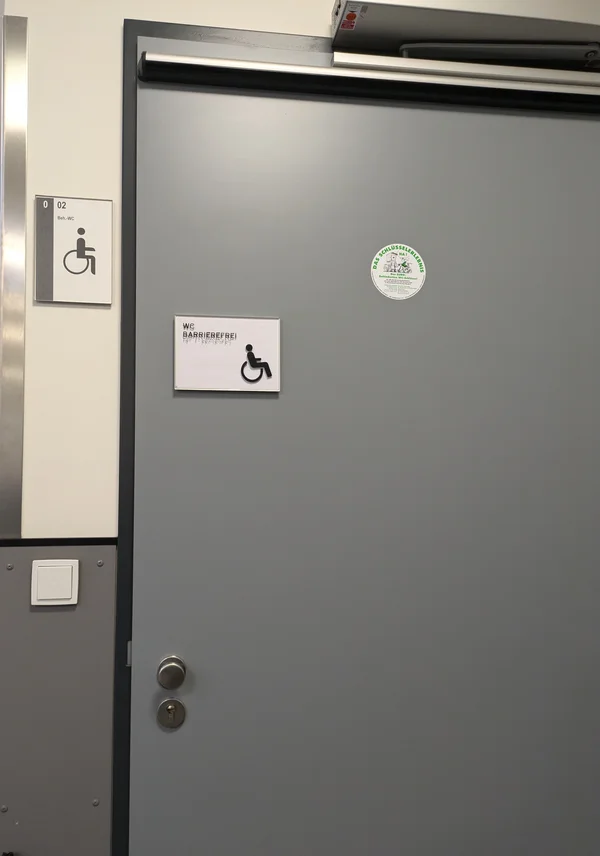 Die geschlossene Tür einer Behindertentoilette von außen.