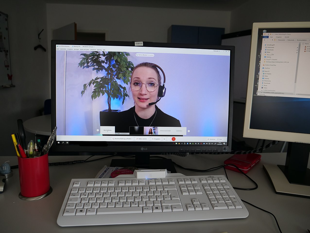 Eine Frau mit Kopfhörer spricht in einer Videokonferenz.